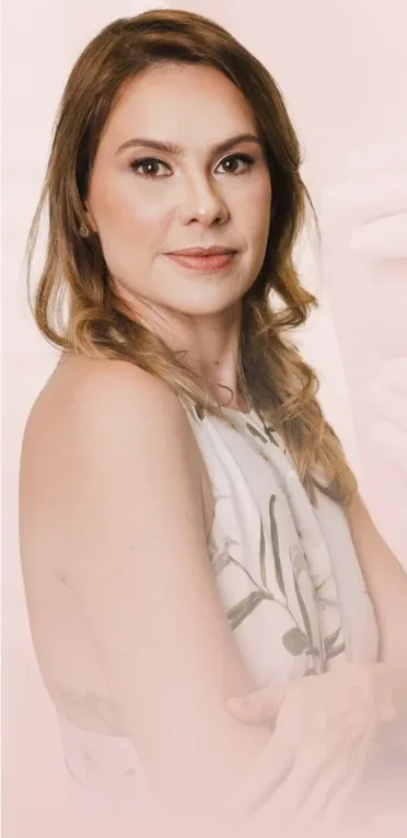 Dra. Camila Macedo Loureiro, de braços cruzados, sorrindo levemente